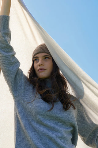 Una ragazza si ripara dal vento con un cappello ed un plaid cecchi e cecchi